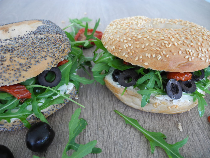 Bagel mit Frischkäse, Ruccola, Oliven und getrockneten Tomaten