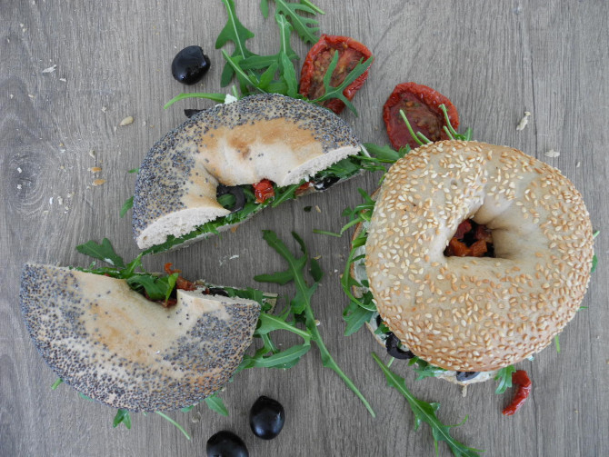 Bagel mit Frischkäse, Ruccola, Oliven und getrockneten Tomaten
