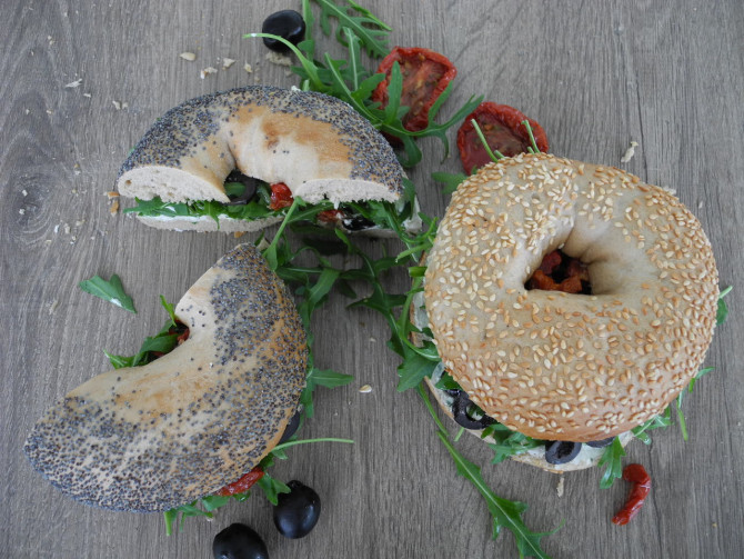 Bagel mit Frischkäse, Ruccola, Oliven und getrockneten Tomaten